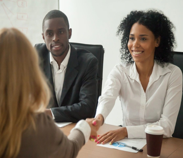 A woman shaking hands with another person at a table.